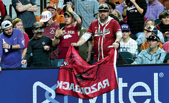 An Arkansas fan displays his Razorback flag in the midst of Texas and TCU fans in Arlington at Globe Life Field during a game between Texas and Arkansas.